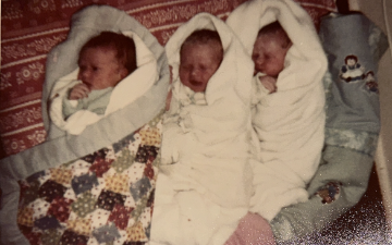 Lowrey Infants: Triplets Rebecca, Jessica, and Rachael laying side by side swaddled in baby blankets. Photos by 