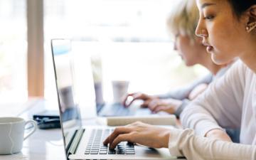 Two women looking at their laptops. Photo credit: Ketut Subiyanto/Pexels 
