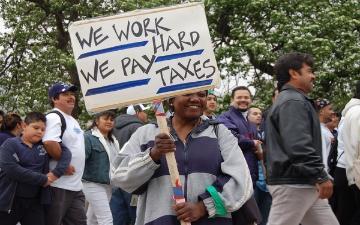 man holds sign supporting immigration and citizenship