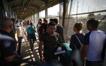 people waiting at immigration checkpoint at the U.S./Mexico border