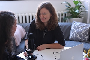 Young woman in black shirt interviewing a peer 