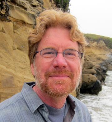 A person standing by rocky cliffs and the ocean.