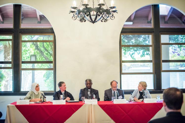 Five panelists sitting at a table in a conference room.