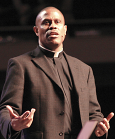 A person speaking or presenting, holding papers. image link to story