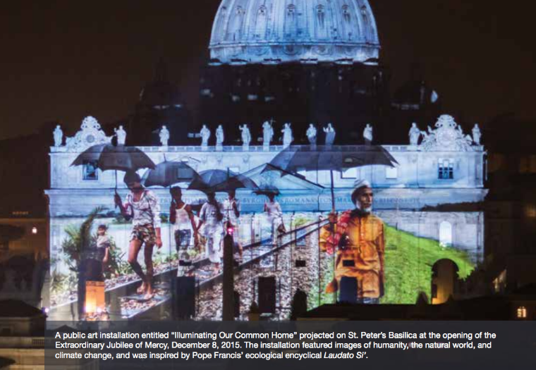 Illuminated building with vibrant projection mapping art and text overlay at the bottom.