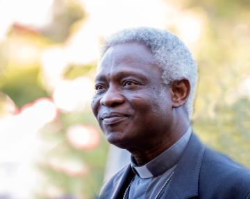 A man in a suit smiling outdoors.