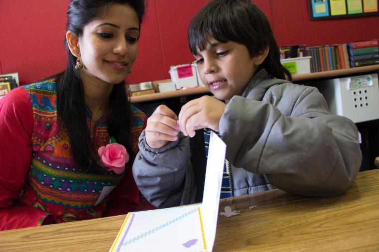 Two people looking at a paper together in a classroom.