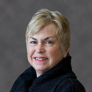 A person smiling against a gray background.