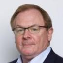 A person wearing glasses, a blue shirt, and a dark jacket.