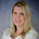 A smiling person with long hair in a white shirt.