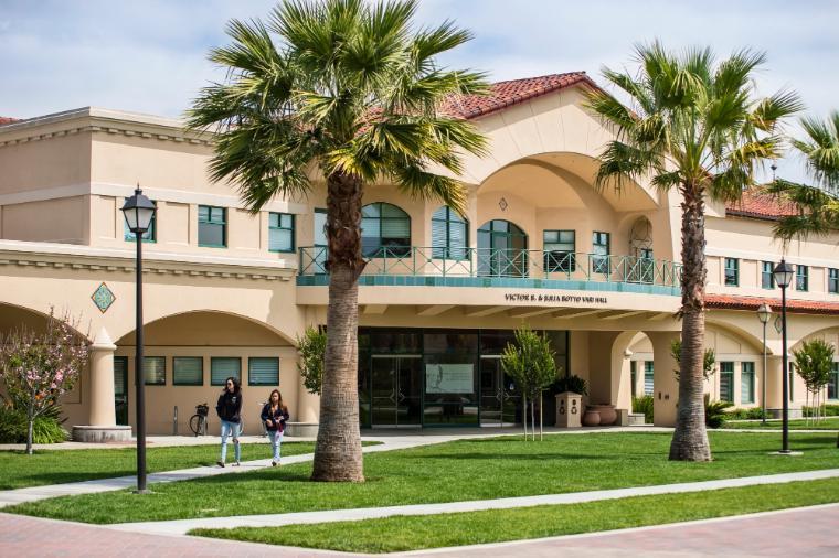 A college building with palm trees in the foreground.