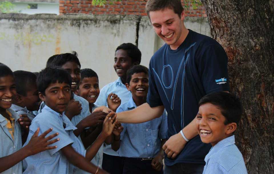 A group of children and an adult standing together outdoors.