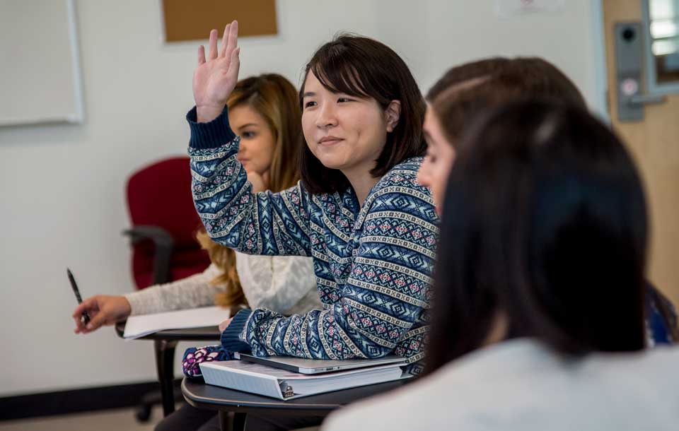 student raising hand in classroom 