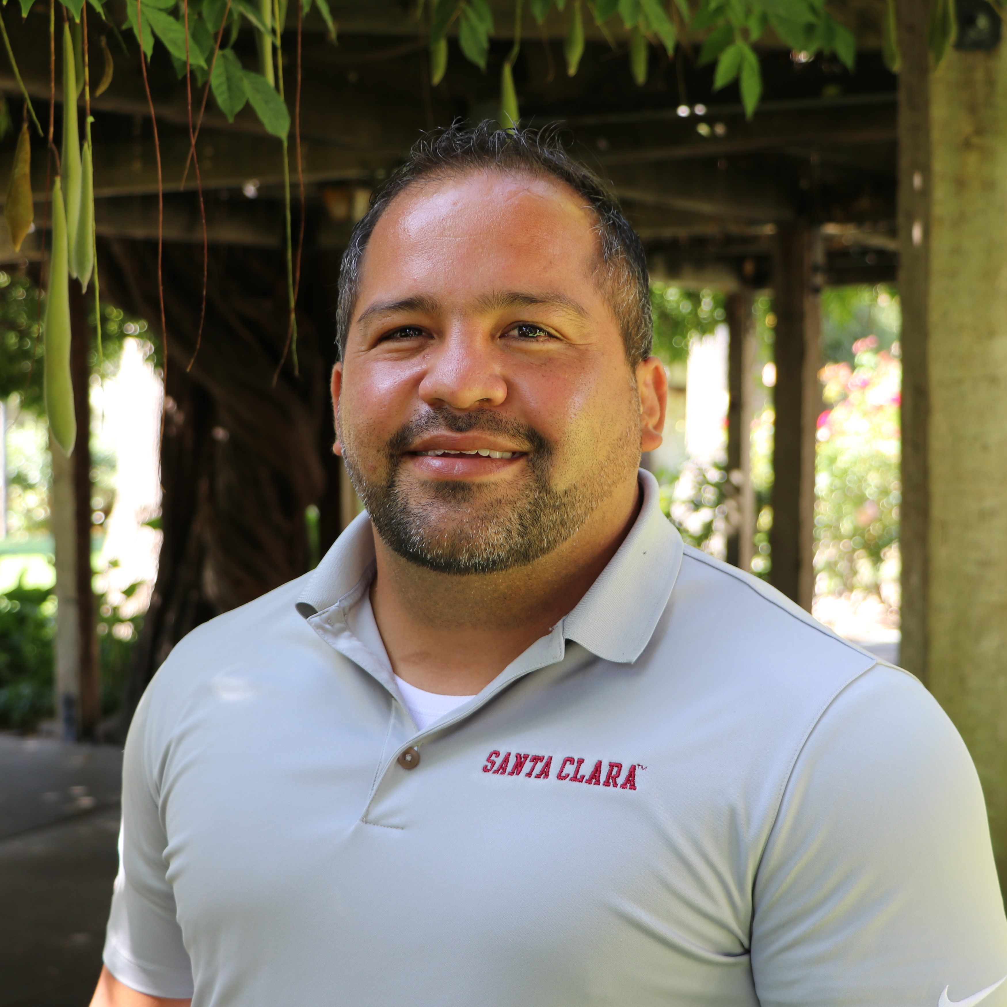 A person wearing a gray shirt, standing outdoors.