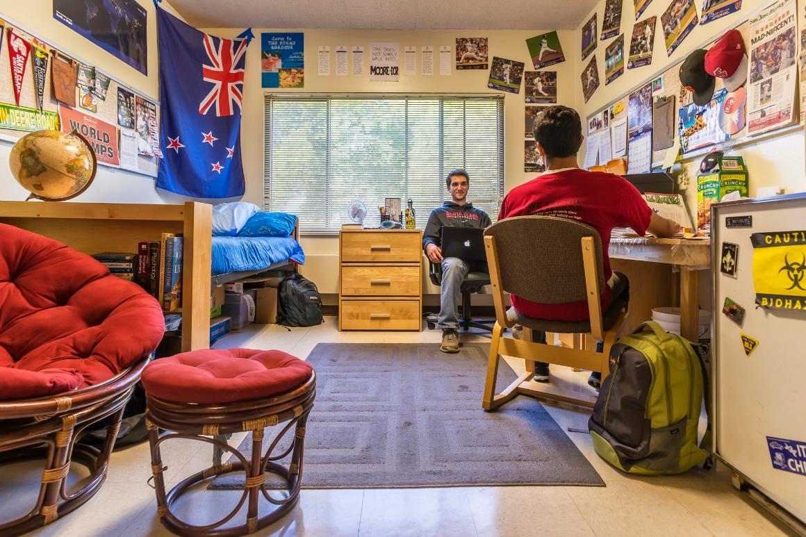 Two people studying in a decorated dorm room with colorful seating.