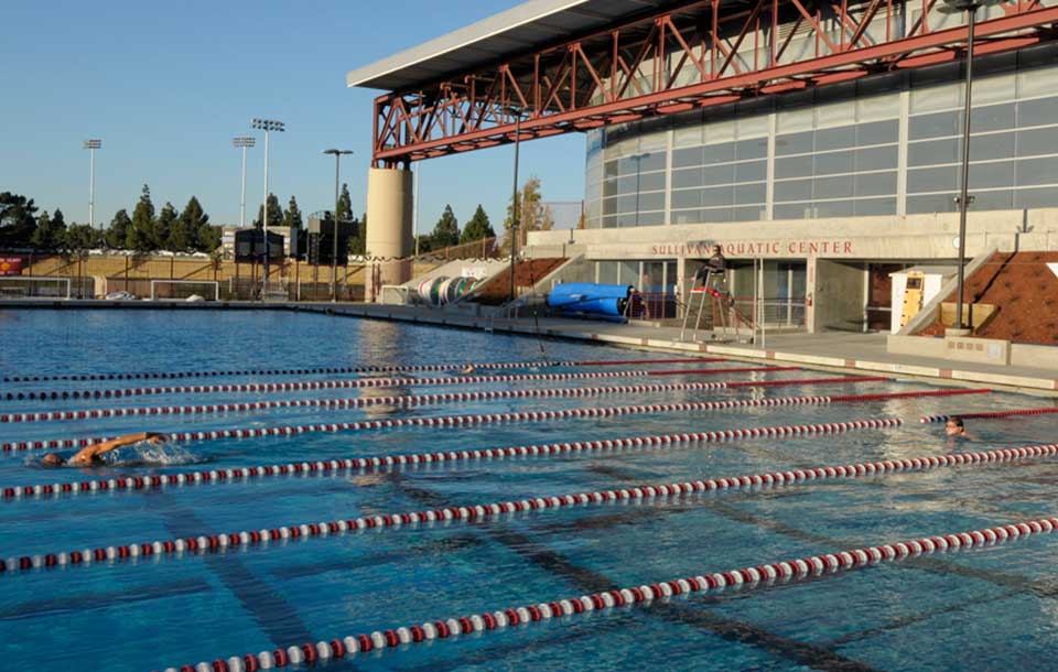 Alt text: Outdoor swimming pool at an aquatic center with lanes and starting blocks.