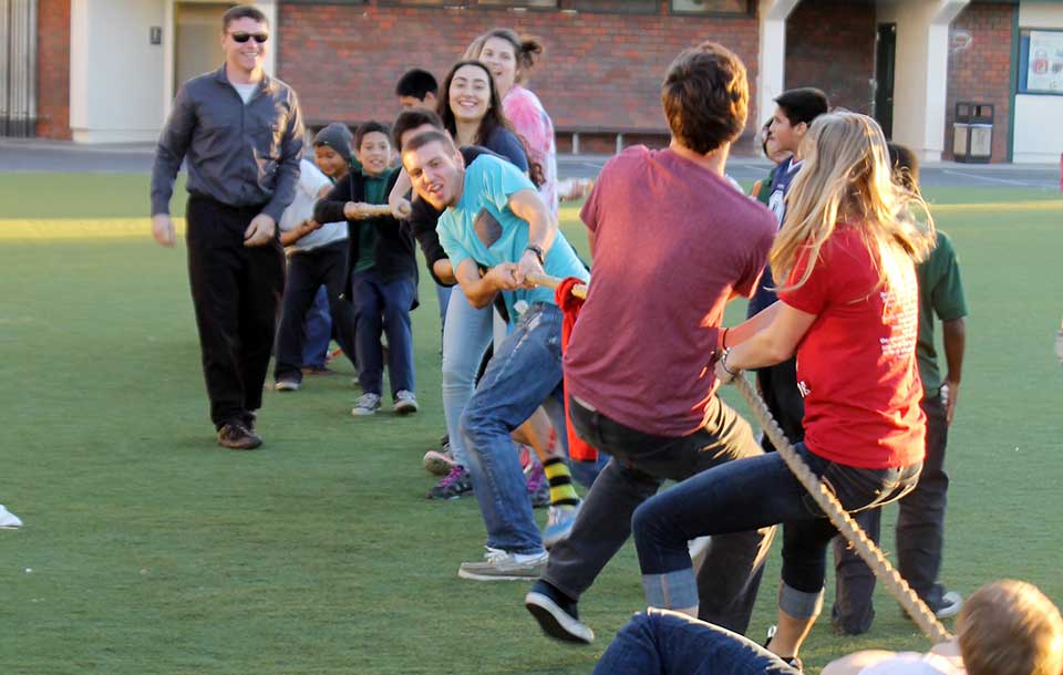 People playing tug of war on a grassy field.