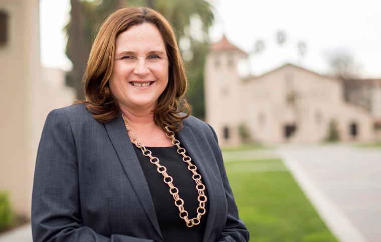 A person in a professional setting smiling at the camera. image link to story