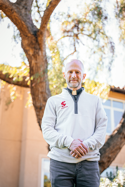 Fr. Matt Carnes standing in front of tree behind Jesuit Residences