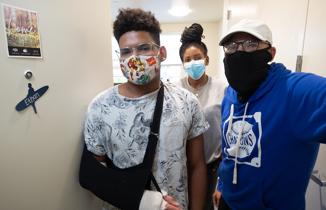 Ethan Evans, '24, stands next to the door of his room inside Graham Hall, with mom Sarah, center, and dad Jonathan Evans, right. Photo by Jim Gensheimer.