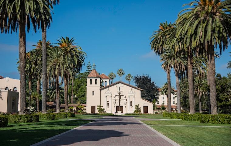 A picturesque campus building with palm trees lining the pathway.