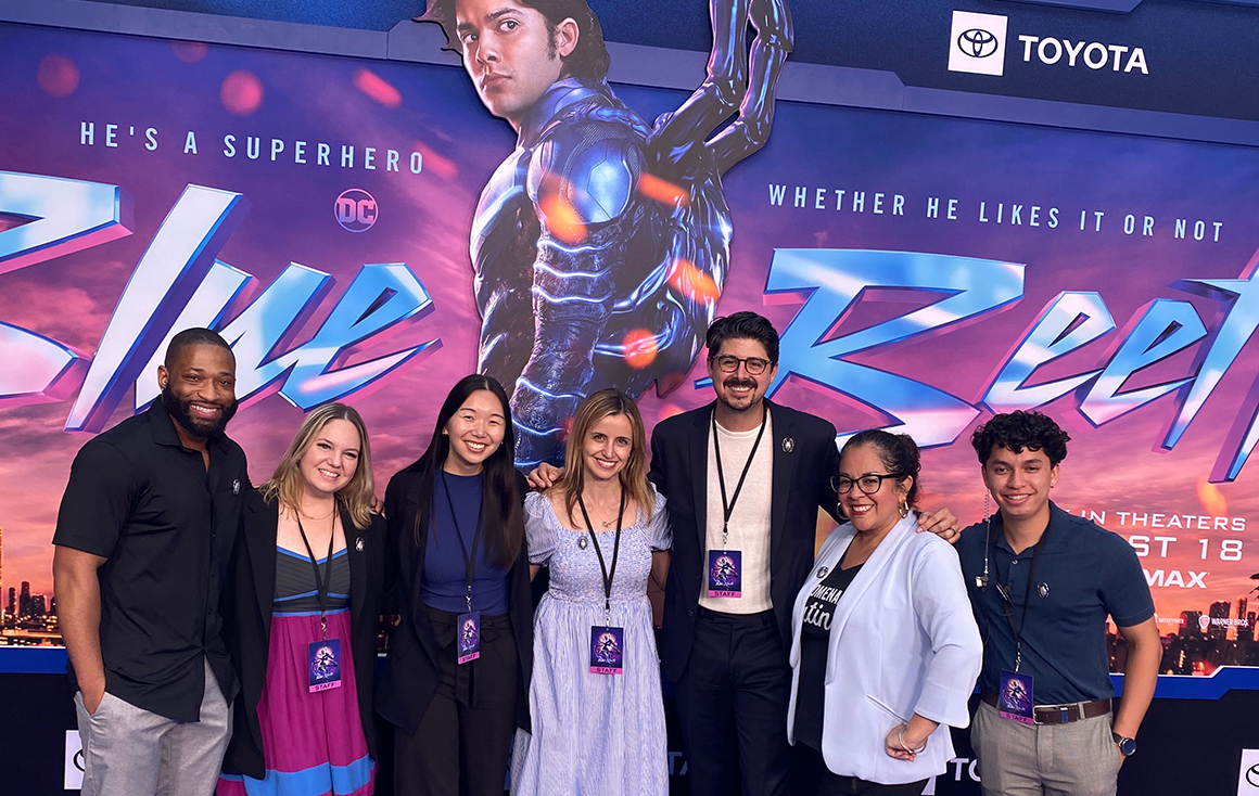 A group of people pose shoulder-to-shoulder in front of a 