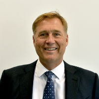 A person in a suit, smiling against a plain background.