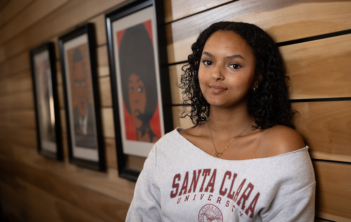 Saron Weldermariam standing against wall wearing Santa Clara University sweatshirt