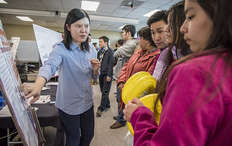 Person presents poster to visitors at eWeek