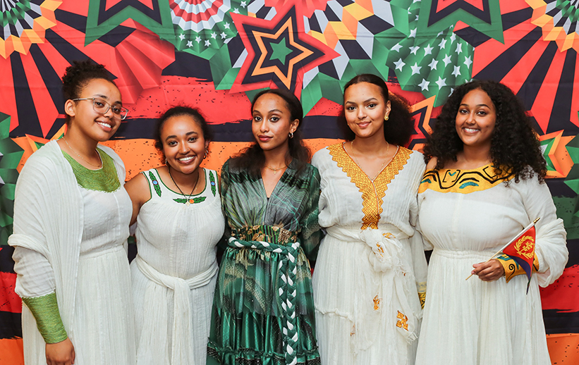 Saron Weldermariam standing with friends in front of brightly painted wall