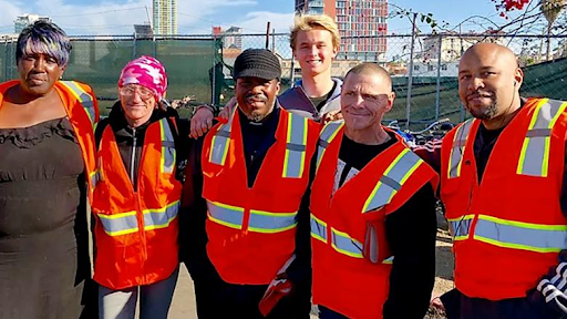 Kevin Barber '23 standing behind 3 Wheels of Change employees