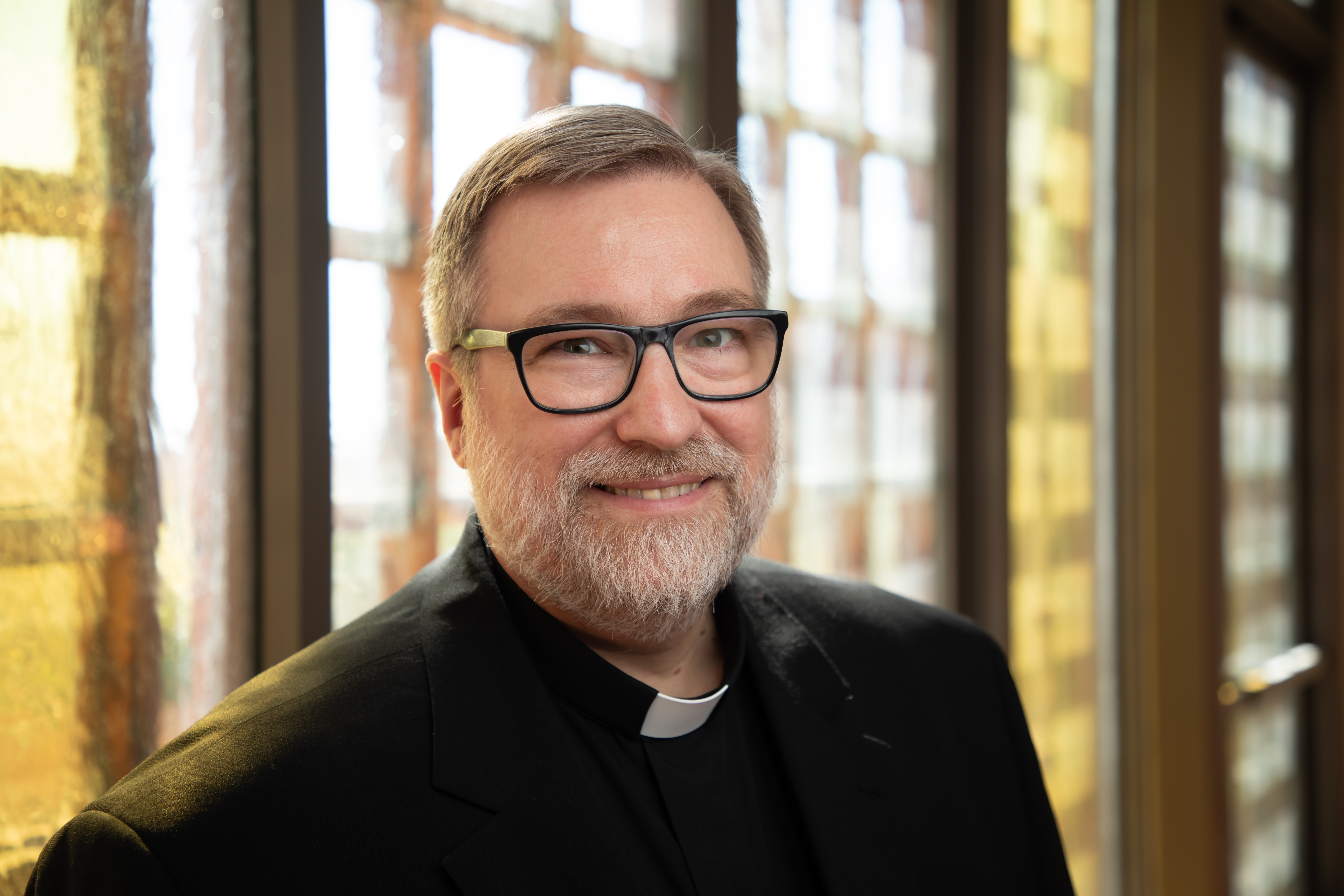 Dean Mueller in front of stain glass doors in JST's chapel