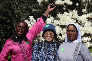 three sabbatical students in front of white flowers 
