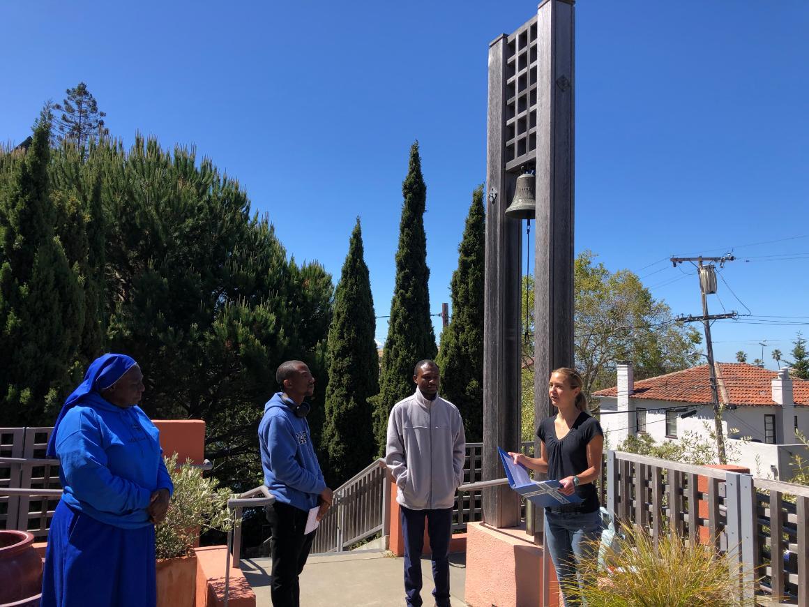 A group of people standing outside near a tall sign that reads 