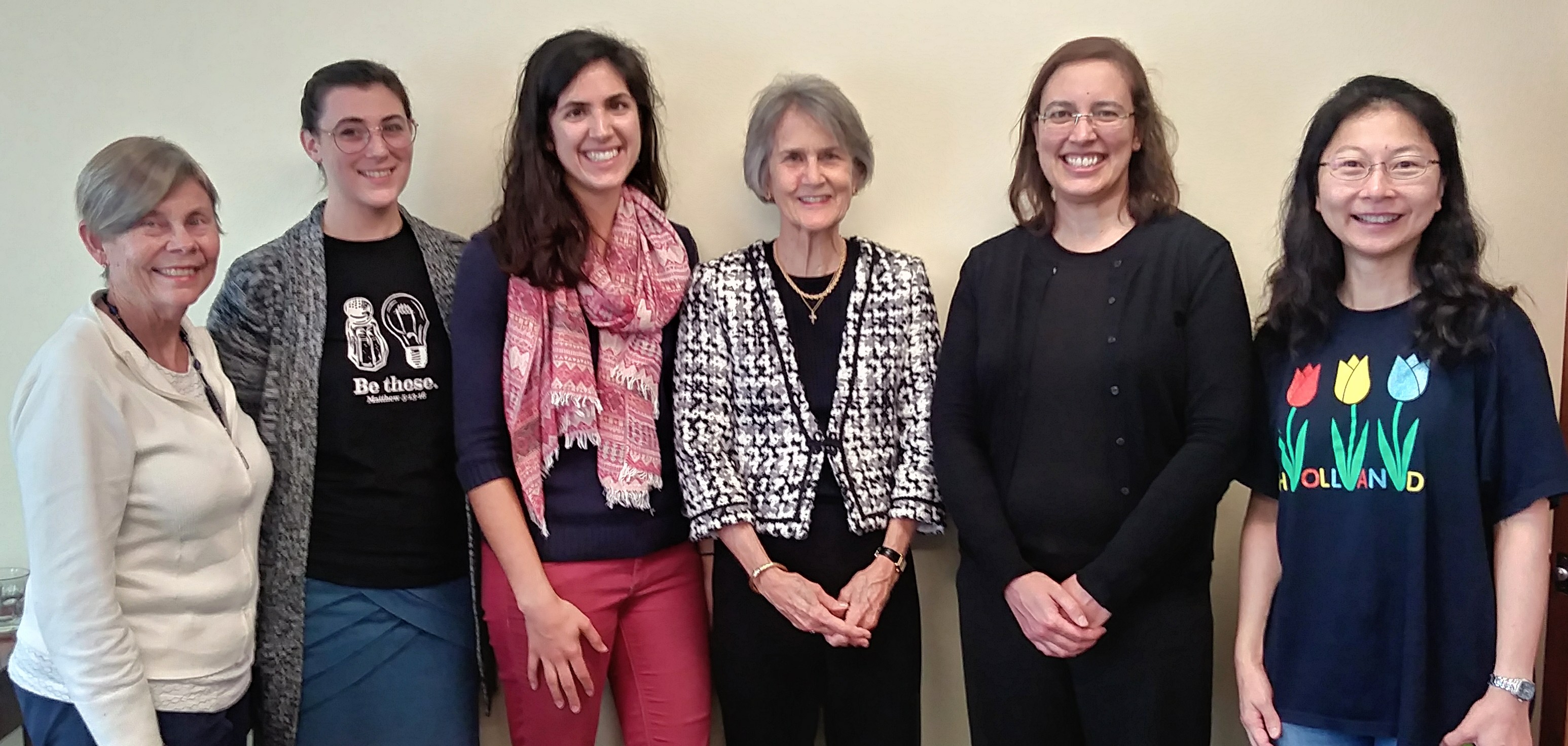 Six women standing together, posing for a group photo at a tea event.
