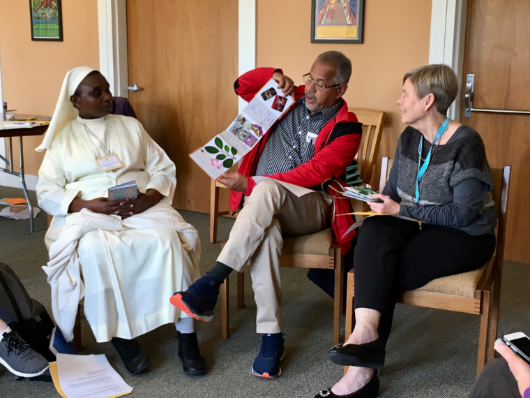 Three people in discussion, one presenting a book titled