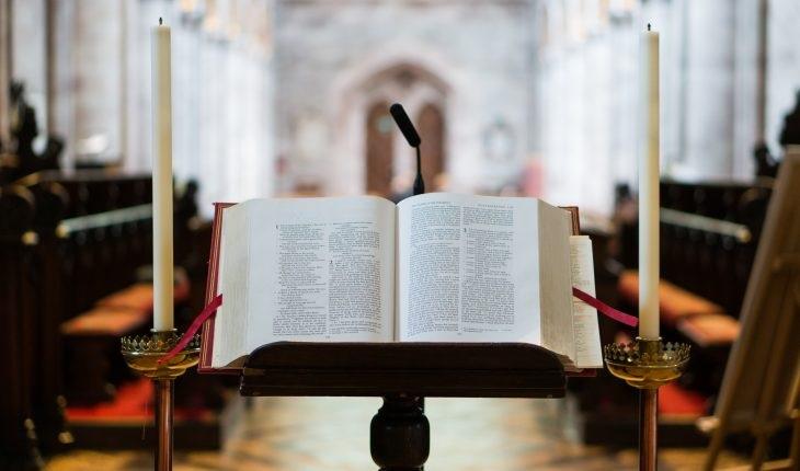Open Bible on church pulpit with candles.