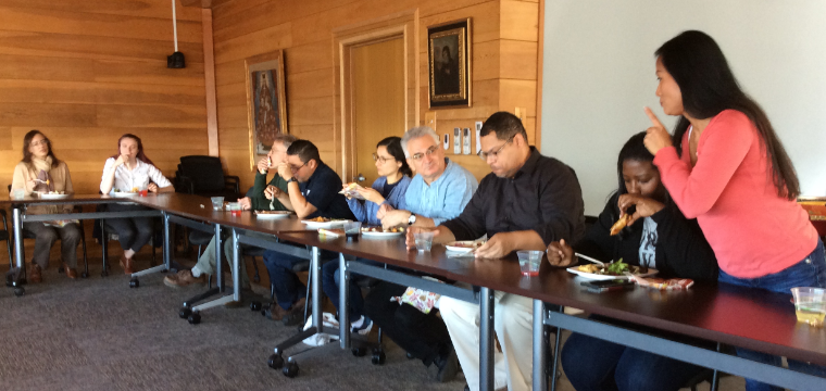 People sitting around a table for a Thanksgiving gathering in a conference room.