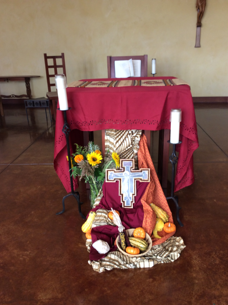 A decorated altar with harvest items, cross, and candles.