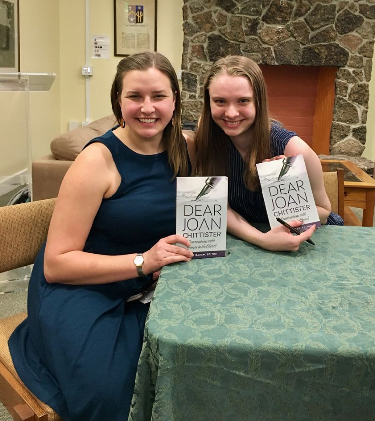 Two people smiling and holding 'Dear Joan' books at a table.
