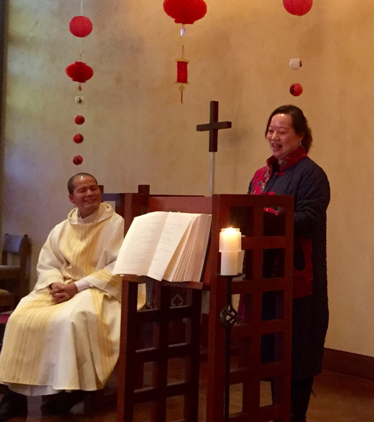 Two people at a church podium during Lunar New Year celebration, decorations hanging.