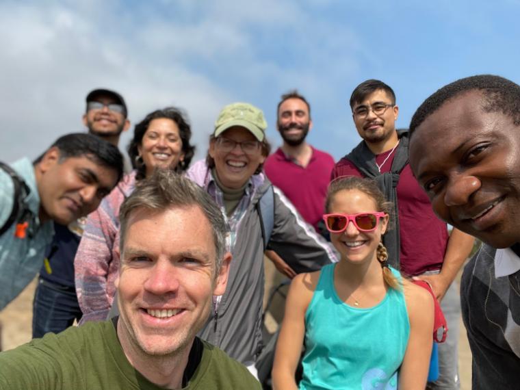 Group of people smiling during a hike; blue sky in the background.