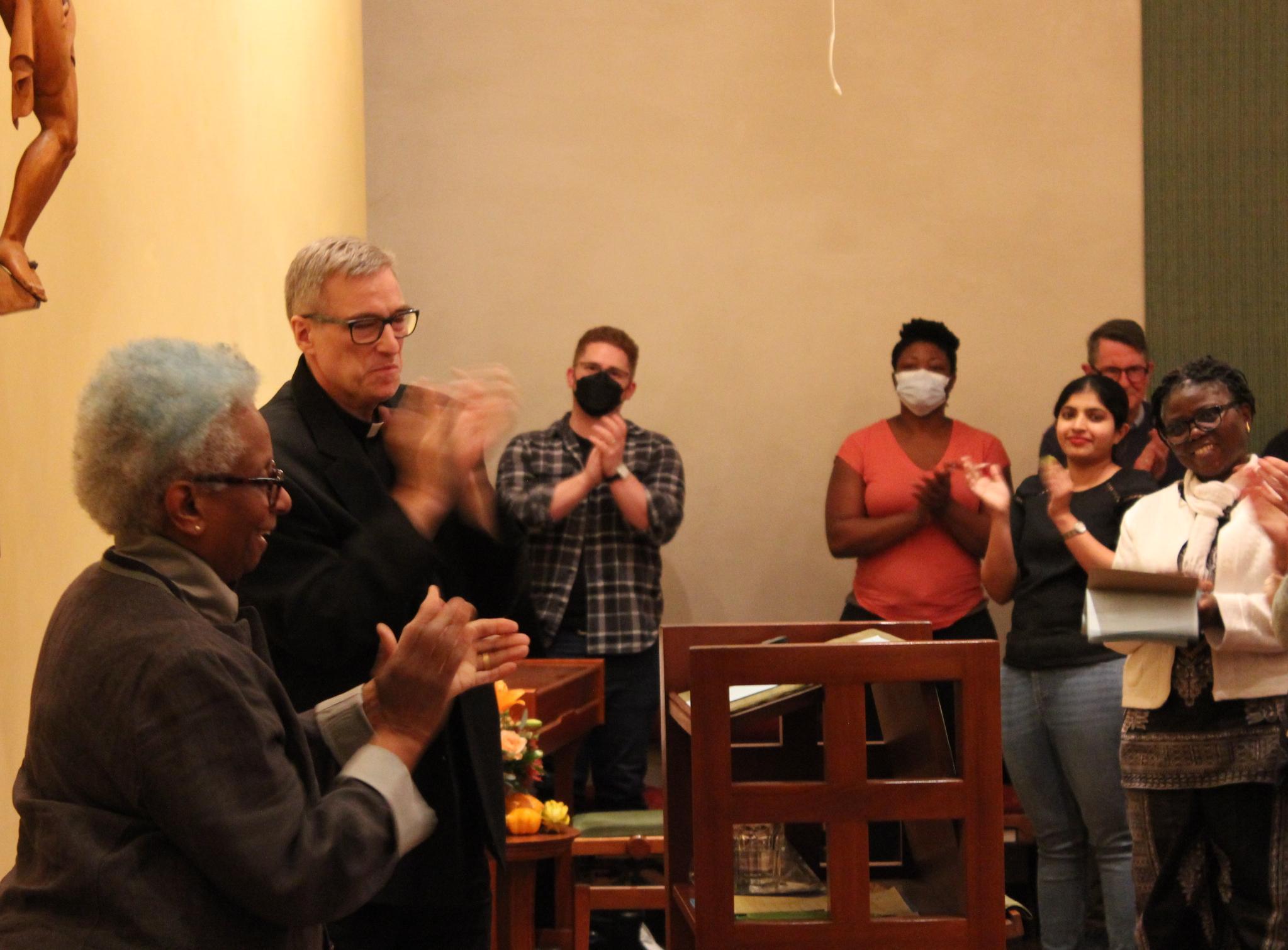 A person speaks to a seated audience in a room.