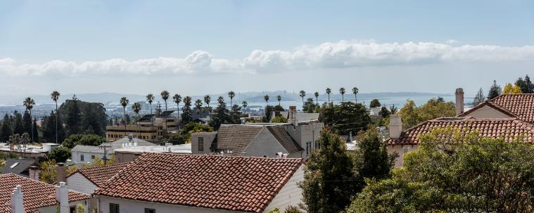View of a cityscape with buildings and trees under a blue sky.