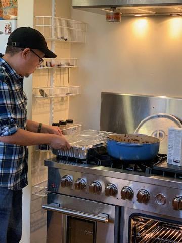 Jesus Munoz cooking with Alexis Dominguez cooking in the background