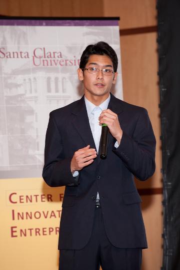 Man in suit delivering a presentation with a microphone.