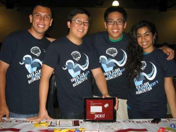 Four team members wearing matching 'SCEO' shirts pose together behind a table.