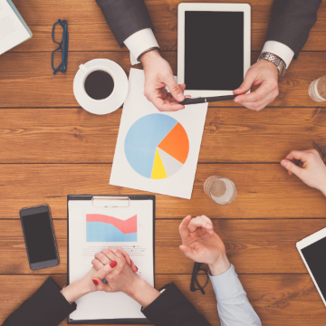 People at a meeting table with charts and tablets.