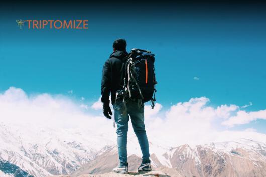 A person with a backpack stands on a snowy mountain.