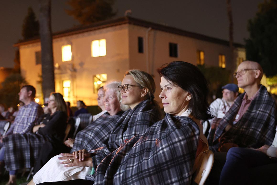 People watching a movie outdoors, wrapped in blankets at night.